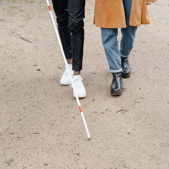 two people walking, one person with a cane