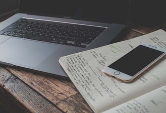 notebook and mobile phone next to laptop on desk