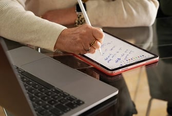 writing on notepad beside laptop