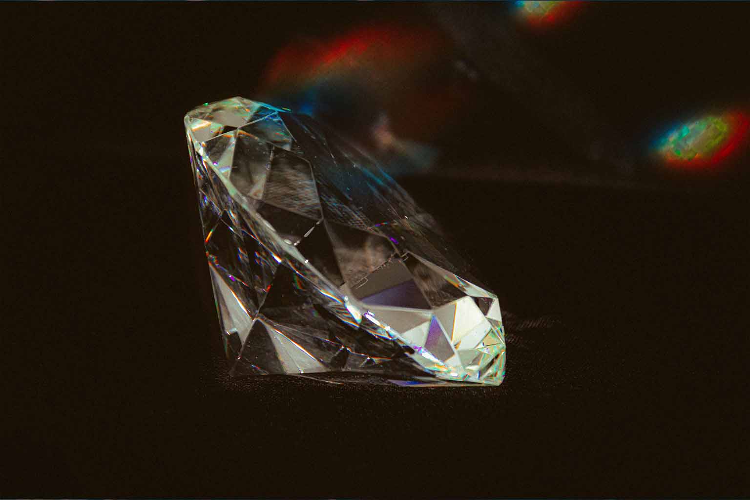 An cut diamond against a black background with a display of rainbow flares