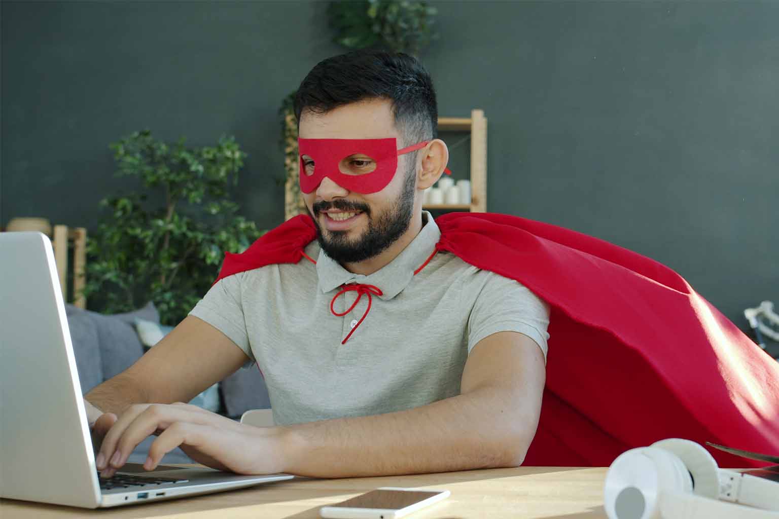 A man in a superhero costume types on a laptop