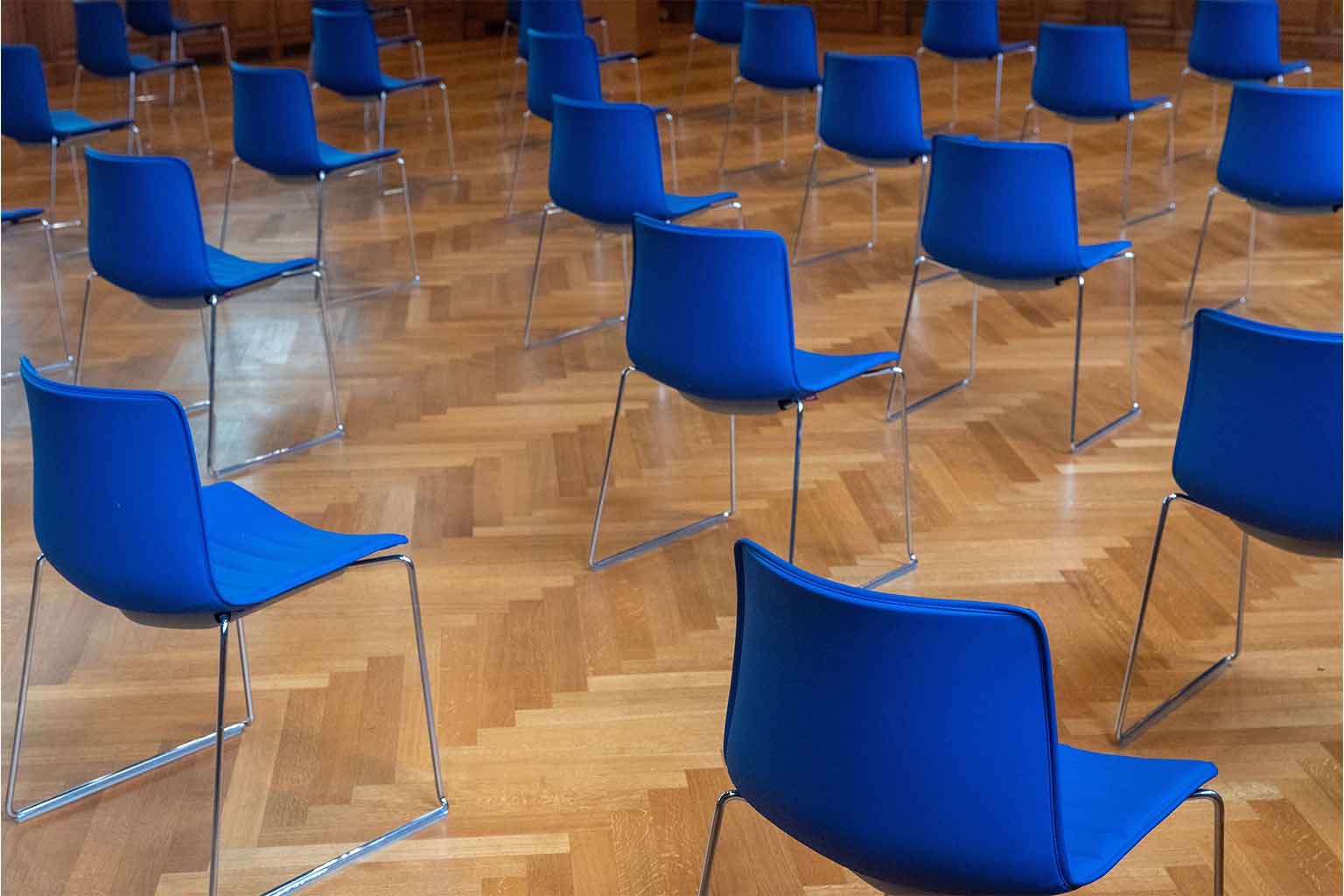 Empty blue seats positioned at an equal distance from one another in an empty room