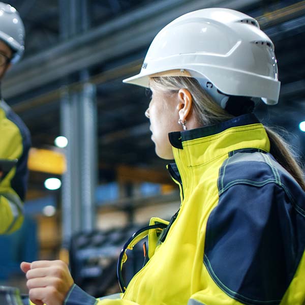 two workers with safety gear on in workhop two workers with safety gear on in workhop