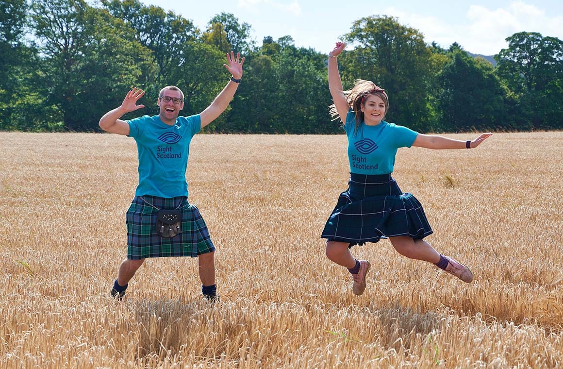 Sight Scotland workers in kilts jumping in field