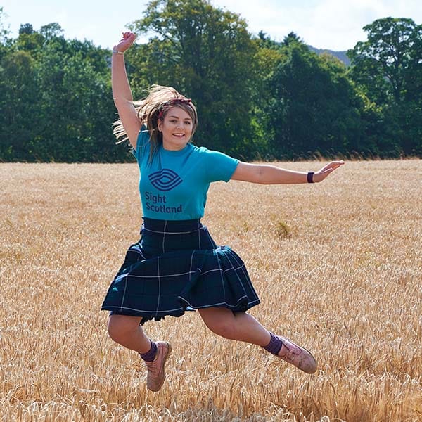Sight Scotland workers in kilts jumping in field