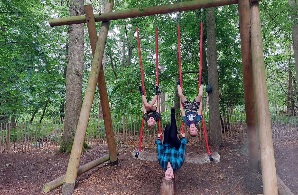 Islamarie and her children hanging upside down on swings