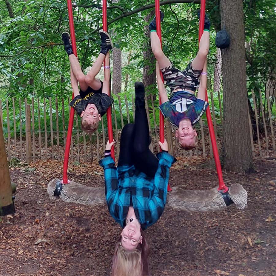 Islamarie and her children hanging upside down on swings